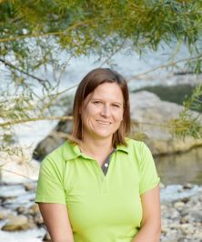 Portrait von Anita, im Hintergrund ein Fluss mit einem darüberhängenden Baum